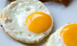 Dwa apetyczne jajka sadzone z płynnym, żółtym żółtkiem i puszystą białkową obwódką, gotowe do zjedzenia.