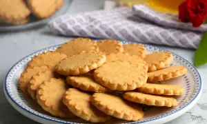 Stos pysznych, złotych kruche ciastka na talerzu z niebieskim wzorem. Idealne na popołudniową herbatkę.
