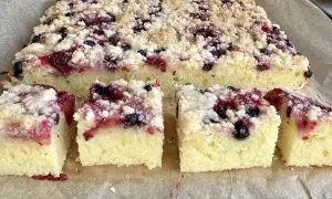 Pyszny placek na maślance z kruszonką i owocami leśnymi, pokrojony na kwadraty.