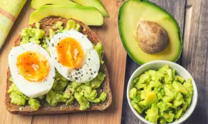 Pyszne awokado jak jeść: tost z rozgniecionym awokado i jajkiem na miękko, obok połówka awokado i miseczka z kawałkami awokado.