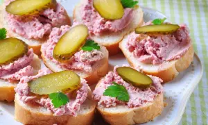 Pyszna pasta na kanapki z ogórkiem kiszonym i natką pietruszki, ułożona na kromkach chleba.