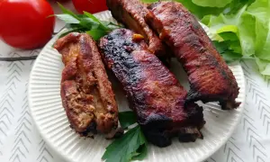 Soczyste żeberka w coli, pieczone do perfekcji, podane z pomidorami i sałatą.