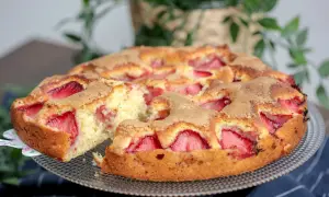 Puszyste ciasto z truskawkami, z kawałkiem już wyjętym, prezentuje się apetycznie. Idealne na letnie popołudnie.