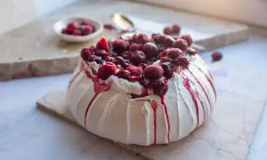Jak piec beze? Puszysta Pavlova z kremem i wiśniami, ozdobiona syropem. Idealna na deser.