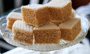 Słodki wafel z mlekiem w proszku, pokrojony w kostkę, ułożony na szklanej paterze.