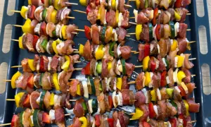 Gotowe do pieczenia szaszłyki z piekarnika: kawałki mięsa, papryki, cebuli i cukinii na patyczkach.