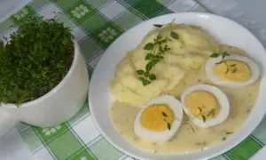 Pyszne puree ziemniaczane z jajkami w sosie chrzanowym, udekorowane świeżym tymiankiem. Obok doniczka z rzeżuchą.