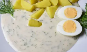 Ziemniaki i jajka w kremowym sosie koperkowym, udekorowane gałązkami koperku.