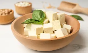 Kostki tofu w misce, ozdobione listkiem bazylii. Czy tofu można jeść na surowo? Tak, to świetna baza do sałatek.