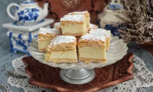Kremowe napoleon ciasto, posypane cukrem pudrem, prezentuje się apetycznie na paterze.