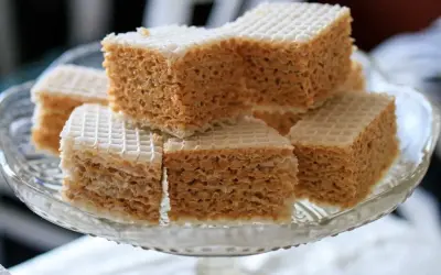 Słodki wafel z mlekiem w proszku, pokrojony w kostkę, ułożony na szklanej paterze.