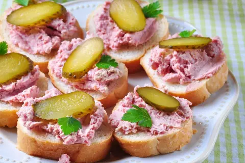 Pyszna pasta na kanapki z ogórkiem kiszonym i natką pietruszki, ułożona na kromkach chleba.
