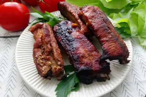 Soczyste żeberka w coli, pieczone do perfekcji, podane z pomidorami i sałatą.