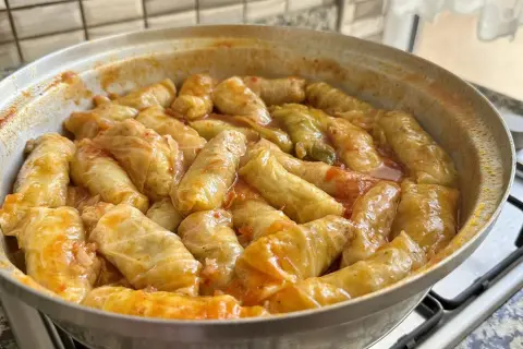 Gołąbki w sosie pomidorowym, gotujące się w garnku. Pyszny sos do gołąbków sprawia, że danie jest aromatyczne i soczyste.