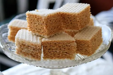 Słodki wafel z mlekiem w proszku, pokrojony w kostkę, ułożony na szklanej paterze.