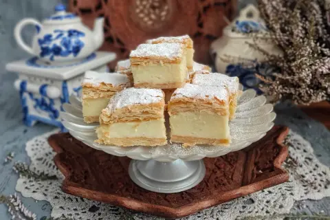 Kremowe napoleon ciasto, posypane cukrem pudrem, prezentuje się apetycznie na paterze.