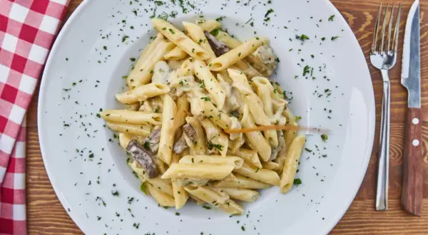 Penne z kremowym sosem grzybowym, posypane natką pietruszki. Idealne, gdy zastanawiasz się, jakie przyprawy do sosu grzybowego wybrać.