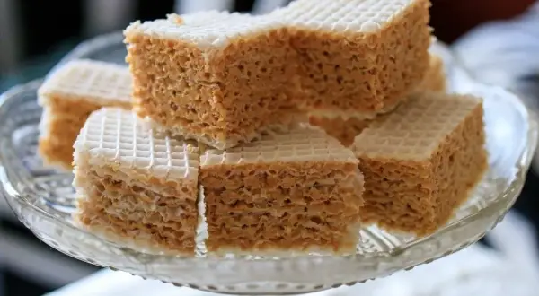 Słodki wafel z mlekiem w proszku, pokrojony w kostkę, ułożony na szklanej paterze.