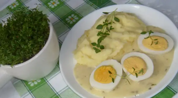 Pyszne puree ziemniaczane z jajkami w sosie chrzanowym, udekorowane świeżym tymiankiem. Obok doniczka z rzeżuchą.