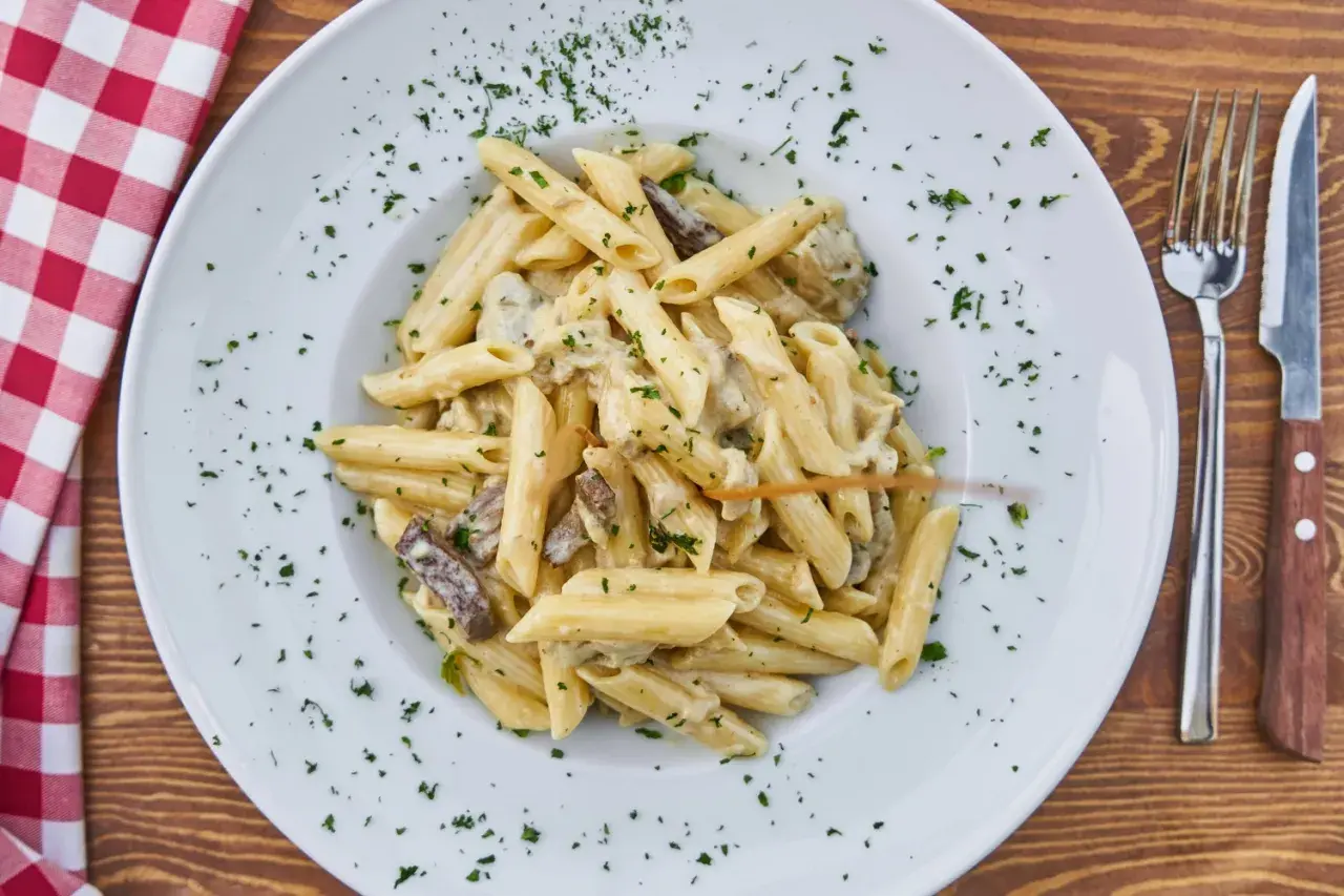 Penne z kremowym sosem grzybowym, posypane natką pietruszki. Idealne, gdy zastanawiasz się, jakie przyprawy do sosu grzybowego wybrać.