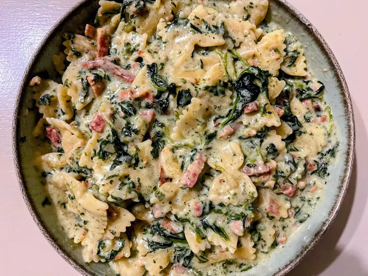 Makaron farfalle w kremowym sosie szpinakowym z kawałkami boczku. Pyszne danie, kt&oacute;re zachwyci każdego miłośnika włoskich smak&oacute;w.