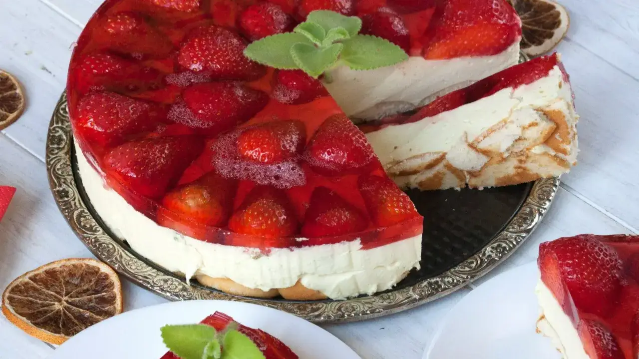 Pyszny sernik na zimno z truskawkami, ozdobiony miętą. Idealny na letnie popołudnie.
