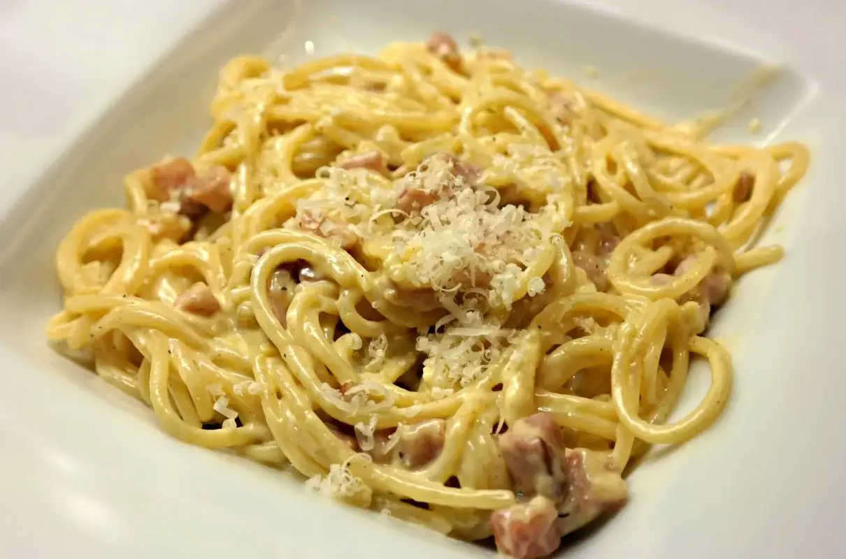Pyszne spaghetti carbonara z kawałkami guanciale i parmezanem. Idealna odpowiedź na pytanie: jaka śmietana do carbonary? (choć tradycyjnie nie używa się śmietany).
