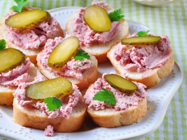 Pyszna pasta na kanapki z ogórkiem kiszonym i natką pietruszki, ułożona na kromkach chleba.