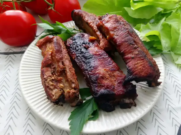Soczyste żeberka w coli, pieczone do perfekcji, podane z pomidorami i sałatą.
